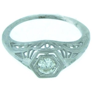 May include: A silver filigree ring with a single round diamond in the center.