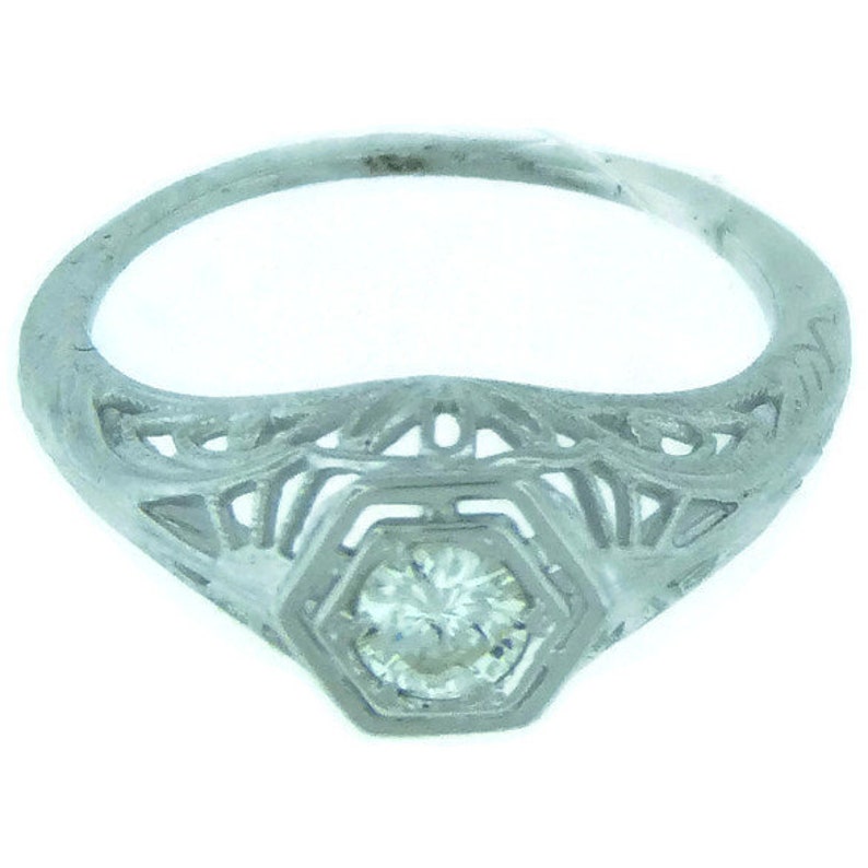May include: A silver filigree ring with a single round diamond in the center.