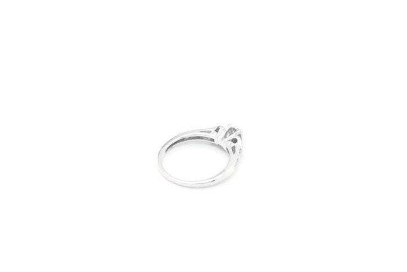 May include: A silver ring with a large, clear center stone and smaller stones on the band.