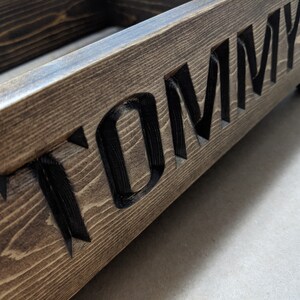 May include: A wooden box with the name "TOMMY" carved into the front. The box is stained a dark brown color.