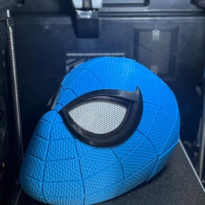 May include: A blue Spider-Man mask with a textured surface and black eye frames. The mask is on a 3D printer. The print size is 270x270x256mm.