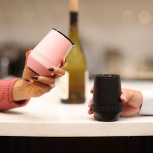 Puede incluir: Dos vasos de vino aislados, uno rosa y otro negro, est&aacute;n siendo sostenidos por dos personas. Los vasos tienen un dise&ntilde;o texturizado y son perfectos para mantener las bebidas fr&iacute;as o calientes.