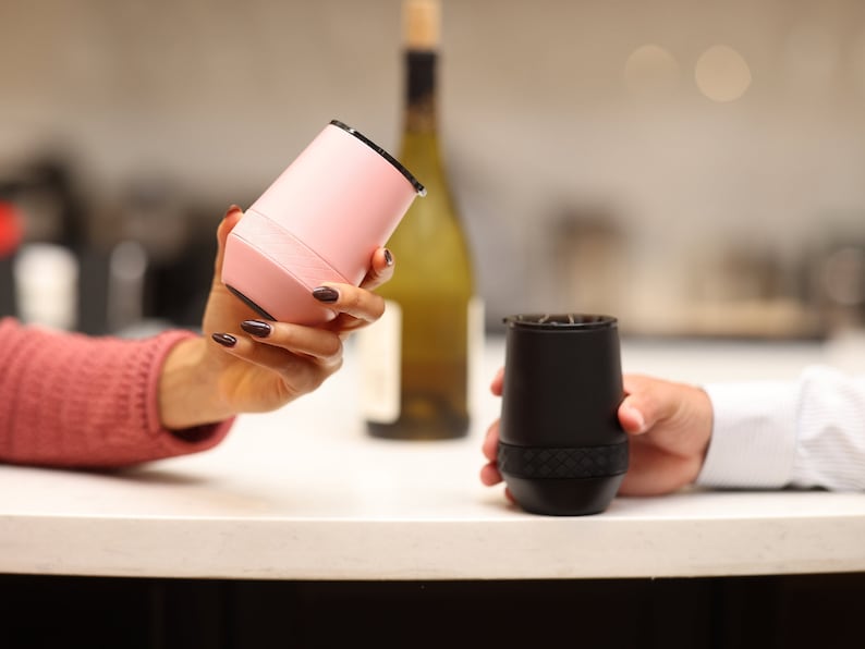 Puede incluir: Dos vasos de vino aislados, uno rosa y otro negro, est&aacute;n siendo sostenidos por dos personas. Los vasos tienen un dise&ntilde;o texturizado y son perfectos para mantener las bebidas fr&iacute;as o calientes.