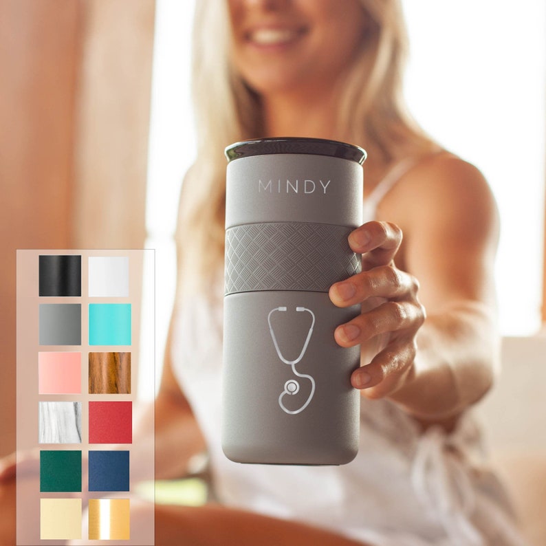 May include: Gray travel mug with a black lid and the word "MINDY" printed on the front. A stethoscope graphic is printed below the word "MINDY".