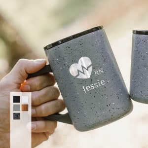 May include: A gray stainless steel travel mug with a speckled finish. The mug has a black lid and a handle. It is personalized with a heart-shaped graphic of a heartbeat and the letters "RN" and the name "Jessie".