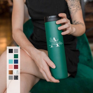 May include: A green stainless steel travel tumbler with a black lid and a silver engraved design featuring the letter "A" and the name "Amelia".