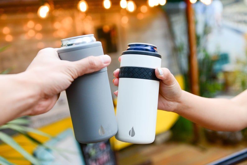 May include: Two people clinking insulated beverage holders, one gray and one white, with a black band and a logo of a water drop.