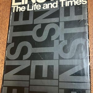 May include: A hardcover book titled Einstein: The Life and Times by Ronald W. Clark. The black dust jacket features the word Einstein in large white letters at the top and repeated in a dark gray vertical pattern across the center of the cover.