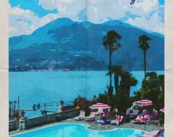 May include: A vintage travel poster with the text "BELLAGIO welcomes you" in red and white. The poster features a blue sky with white clouds, a mountain range, a lake, palm trees, and a swimming pool with people relaxing on lounge chairs.