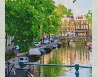 May include: A vintage travel poster featuring a picturesque view of a canal in Amsterdam, Netherlands. The poster features a bicycle in the foreground, a canal with boats, and buildings along the canal. The text on the poster reads "Amsterdam welcomes you" and "Brocktalk Photography".