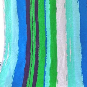 May include: A fabric with a striped pattern in shades of blue, green, and white. The stripes are painted on a white background and have a brushstroke effect.