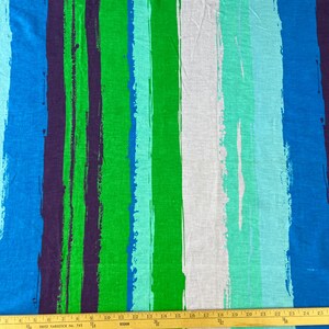 May include: A fabric with a striped pattern in shades of blue, green, and white. The stripes are painted with a brushstroke effect, giving the fabric a textured look.