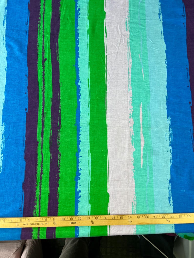 May include: A fabric with a striped pattern in shades of blue, green, and white. The stripes are painted with a brushstroke effect, giving the fabric a textured look.
