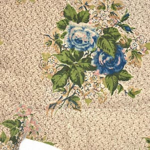 May include: Floral fabric featuring a repeating pattern of small brown vines on a cream background. Large clusters of blue roses with green leaves and small white flowers are scattered across the fabric. The fabric has a vintage aesthetic.