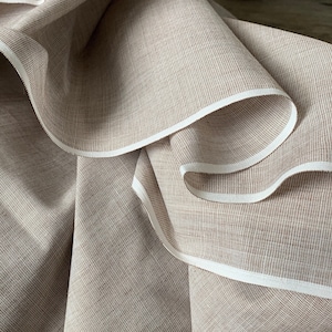 Puede incluir: Primer plano de una tela marrón con ribete blanco. La tela tiene una textura sutil y una sensación ligeramente áspera.