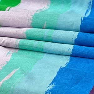 May include: A colorful fabric with a striped pattern. The stripes are painted in shades of green, blue, and purple. The fabric is folded in half.