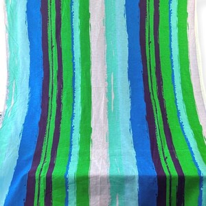 May include: A fabric with a striped pattern in shades of blue, green, and purple. The stripes are painted on a white background.