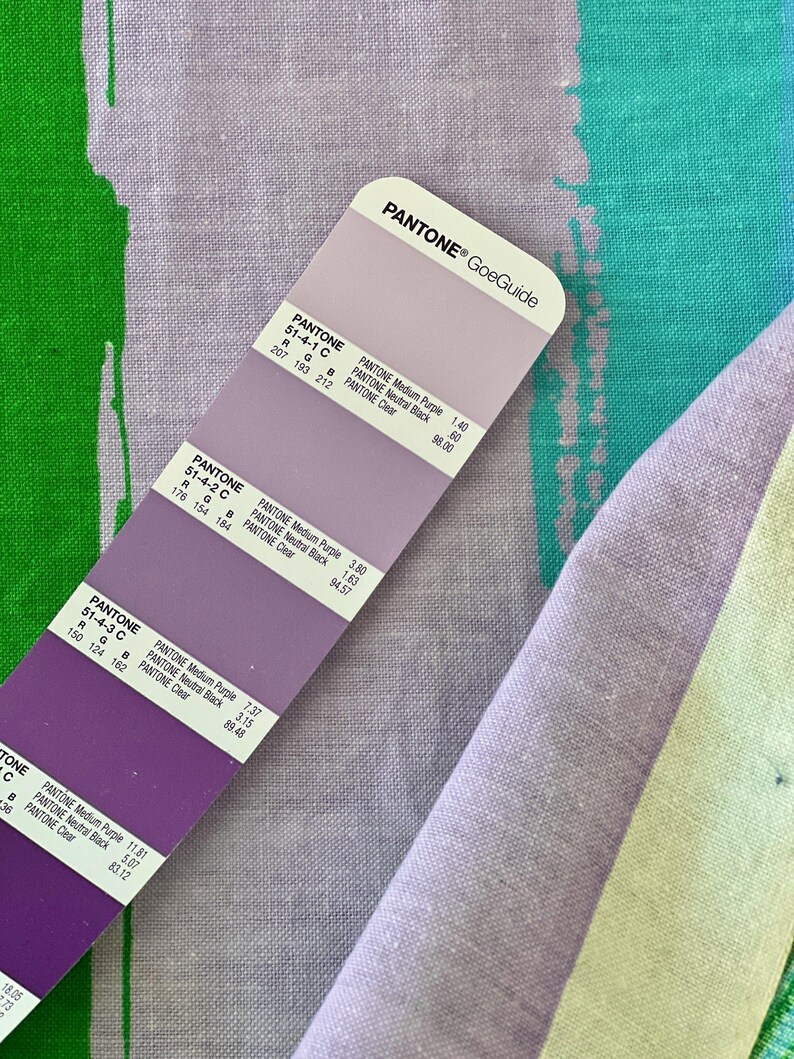 May include: A color swatch card with different shades of purple. The card is labeled "PANTONE&reg; GoeGuide" and includes the Pantone color numbers and names for each shade.