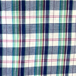 May include: Close-up of a fabric with a plaid pattern. The pattern features a grid of intersecting lines in white, navy blue, teal, green, purple, yellow, and red. The fabric has a slightly wrinkled texture.