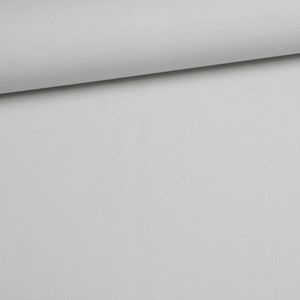 Puede incluir: Una tela de color gris claro s&oacute;lido con una textura suave y uniforme. El material est&aacute; doblado en el borde superior, creando una l&iacute;nea de sombra suave que resalta el acabado mate y el color constante de la superficie textil en la imagen.