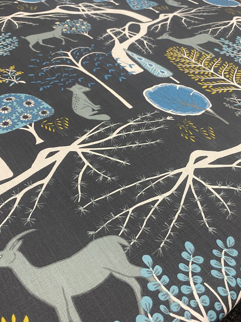 May include: A dark gray fabric with a repeating pattern of stylized trees, deer, and other woodland creatures in shades of blue, white, and yellow.