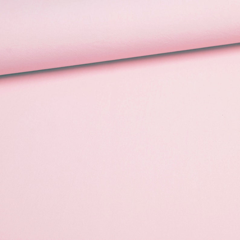 May include: A close-up of a soft, pale pink fabric. The fabric is smooth and has a subtle texture.