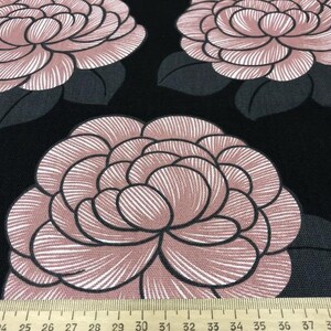 May include: Black fabric with a repeating pattern of large pink and white flowers. The flowers have a detailed, striped design.