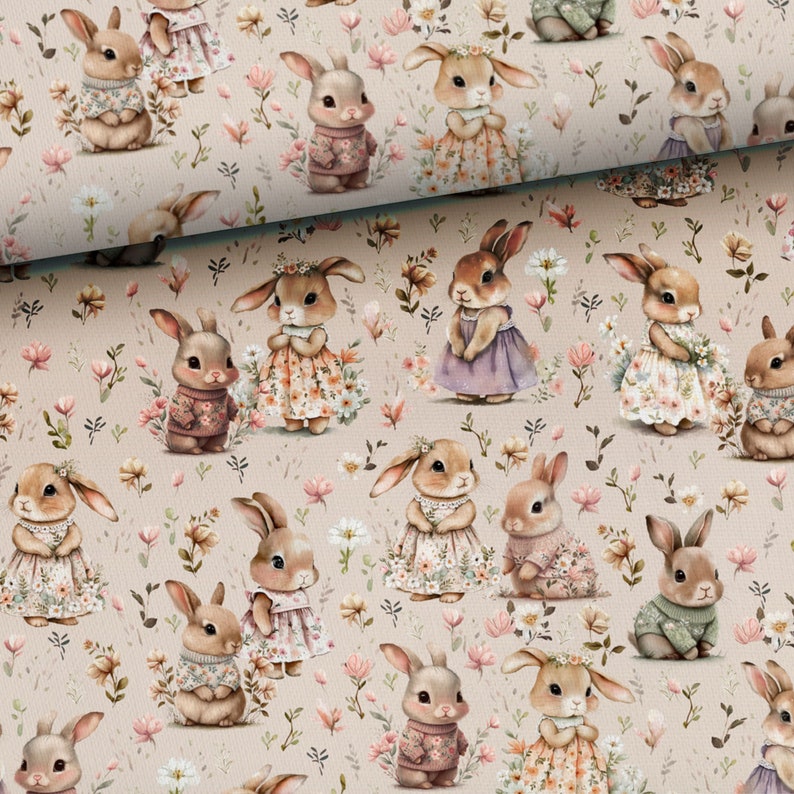 May include: A beige fabric with a repeating pattern of bunnies wearing different outfits and holding flowers. The bunnies are surrounded by pink and white flowers and green leaves.