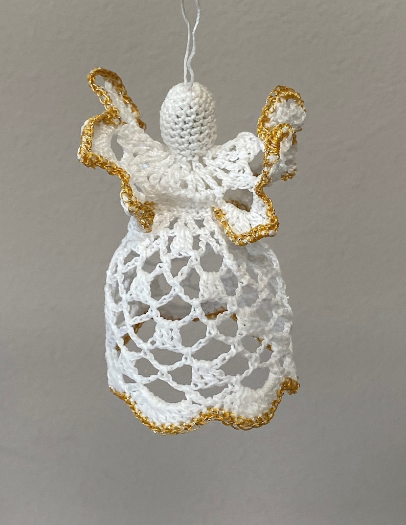 May include: White crocheted angel ornament with gold trim. The angel has a bell-shaped body and outstretched wings.