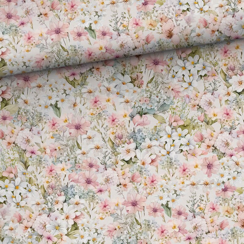 May include: A white fabric with a floral pattern featuring pink and white flowers. The fabric is covered in a variety of flowers, including roses, daisies, and wildflowers.