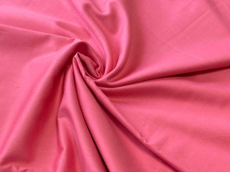 May include: A close-up shot of a vibrant pink fabric with a smooth, silky texture. The fabric is artfully draped and swirled, creating soft folds and shadows. The color is a bright, saturated pink, perfect for apparel or home decor projects.