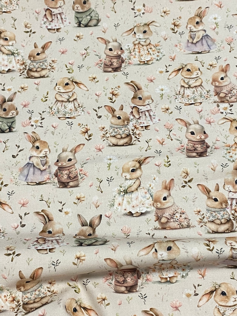 May include: A beige fabric with a repeating pattern of brown rabbits wearing different outfits. The rabbits are surrounded by small green and white flowers.