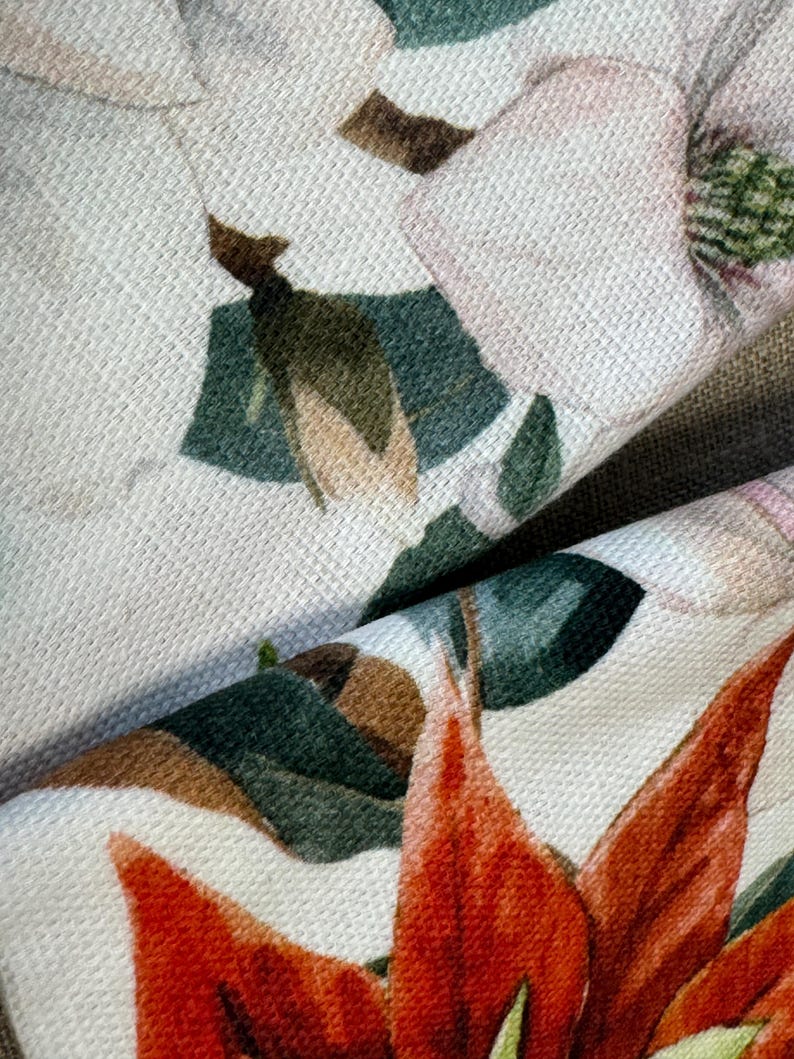 May include: Close-up of a fabric with a floral print. The fabric features a white background with red, green, and pink flowers. The flowers are detailed and realistic.
