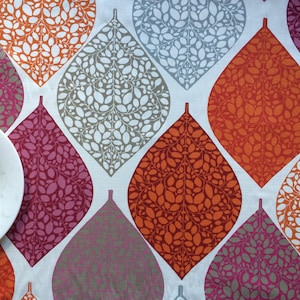 May include: A white tablecloth with a repeating pattern of orange, red, pink, and gray leaf shapes. The leaves are filled with a smaller pattern of white leaves.