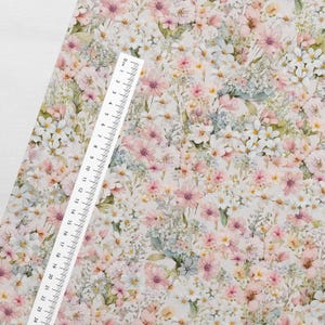 May include: A white fabric with a floral pattern featuring pink, white, and blue flowers. The fabric has a watercolor effect and is perfect for crafting projects.