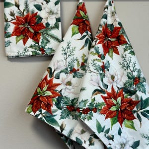 Puede incluir: Tres toallas de cocina blancas con estampado de poinsettia roja, magnolia blanca y bayas de acebo verdes.