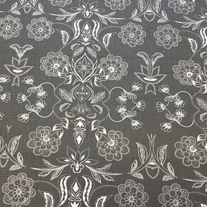 Könnte beinhalten: Ein grauer Stoff mit einem weißen Blumenmuster. Das Muster zeigt komplizierte Designs von Blumen, Blättern und Ranken.