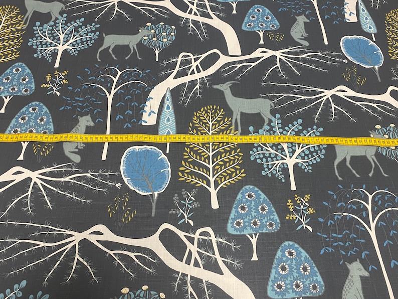 May include: A dark blue fabric with a repeating pattern of white trees, blue and yellow flowers, and deer. The fabric has a subtle texture.