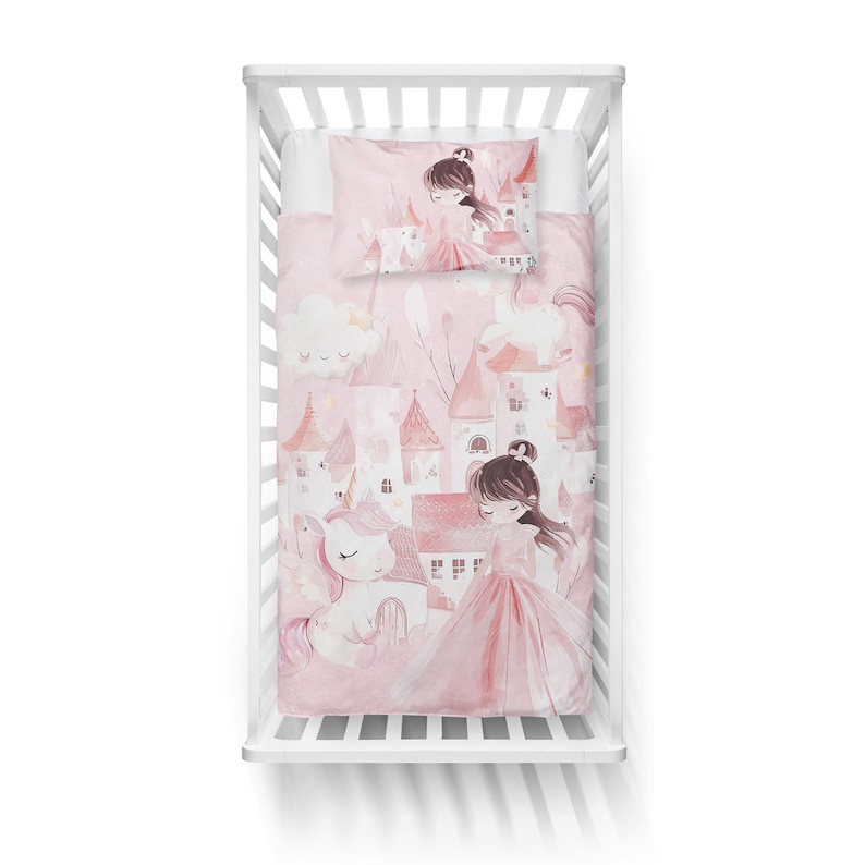 May include: Pink and white crib bedding set featuring a princess and unicorn theme. The set includes a fitted sheet, a comforter with a castle design, and a pillowcase. The design features a princess in a pink dress, unicorns, and castles.