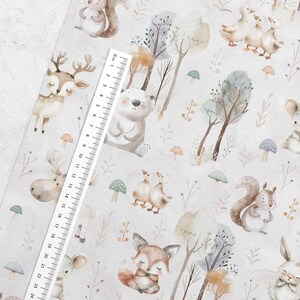 May include: A white fabric with a repeating pattern of watercolor woodland animals, including a deer, a bear, a moose, a fox, a squirrel, and ducks. The fabric also features trees, mushrooms, and leaves.
