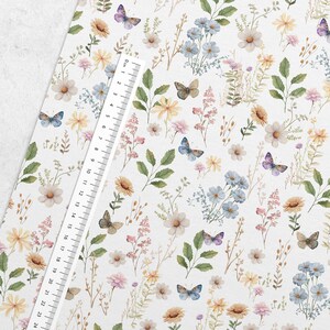 May include: A white fabric with a repeating pattern of watercolor flowers and butterflies. The flowers are in shades of pink, yellow, and blue. The butterflies are in shades of blue, purple, and brown.