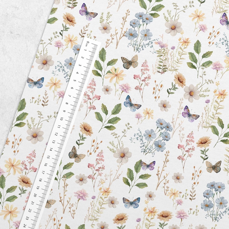 May include: A white fabric with a repeating pattern of watercolor flowers and butterflies. The flowers are in shades of pink, yellow, and blue. The butterflies are in shades of blue, purple, and brown.