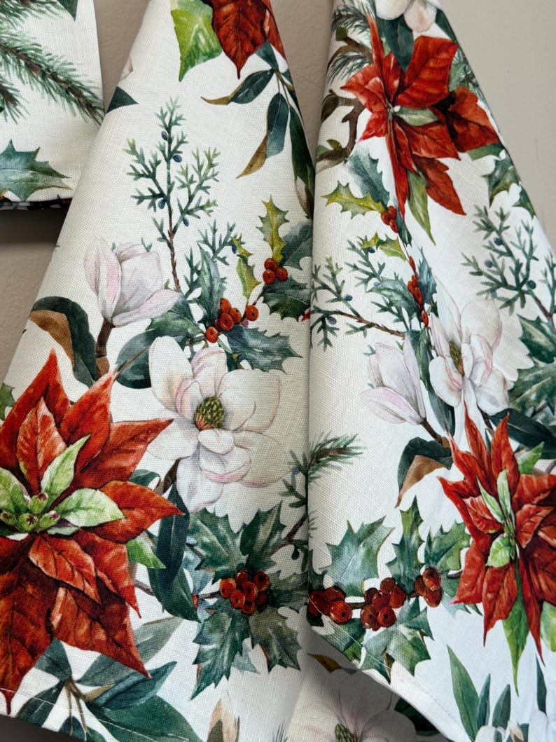 May include: Three white tea towels with a Christmas floral print featuring red poinsettias, white magnolia flowers, green holly leaves, and red berries.