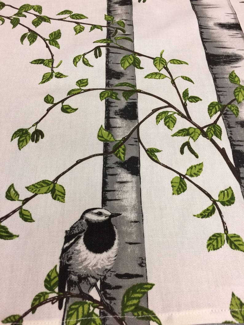 Puede incluir: Un p&aacute;jaro blanco y gris con marcas negras se posa en una rama frente a un fondo blanco con dos abedules grises y blancos y hojas verdes.