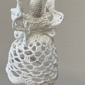 May include: White crocheted angel ornament with a bell-shaped skirt and delicate wings.