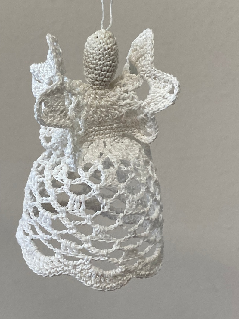 May include: White crocheted angel ornament with a bell-shaped skirt and delicate wings.
