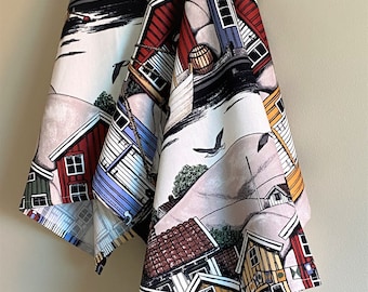 May include: Two white tea towels with a colorful illustration of houses and boats. The houses are red, yellow, blue, and green. The boats are black and white. The background is white with a light gray sky.