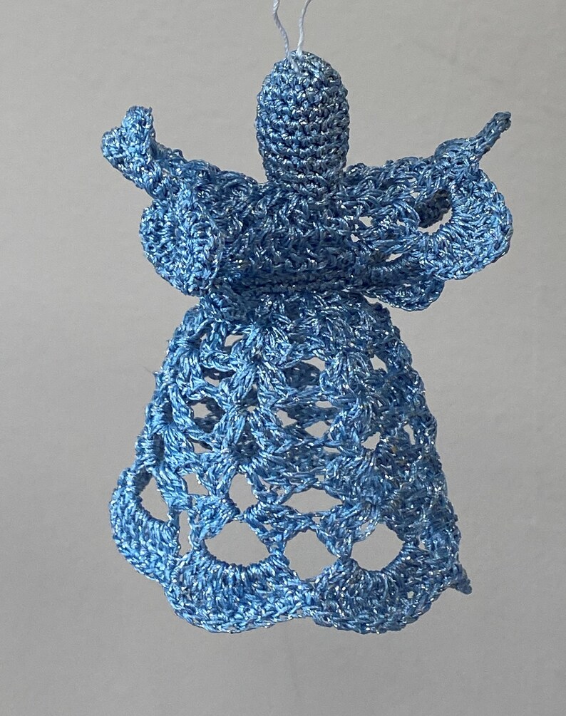 May include: A blue crocheted angel ornament with a delicate, lacy design. The angel has a long, flowing gown and outstretched wings.