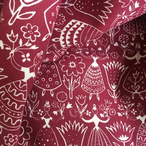 Puede incluir: Tela roja con un patr&oacute;n blanco de figuras y flores estilizadas. Las figuras llevan vestidos y sostienen flores. La tela tiene una superficie texturizada.