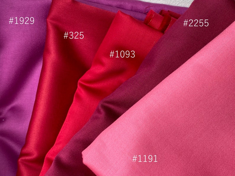 May include: Close-up of fabric swatches in shades of red and purple. The swatches are labeled with numbers: #1929, #325, #1093, #2255, and #1191. The fabrics have a smooth, satin-like texture, with varying degrees of sheen.